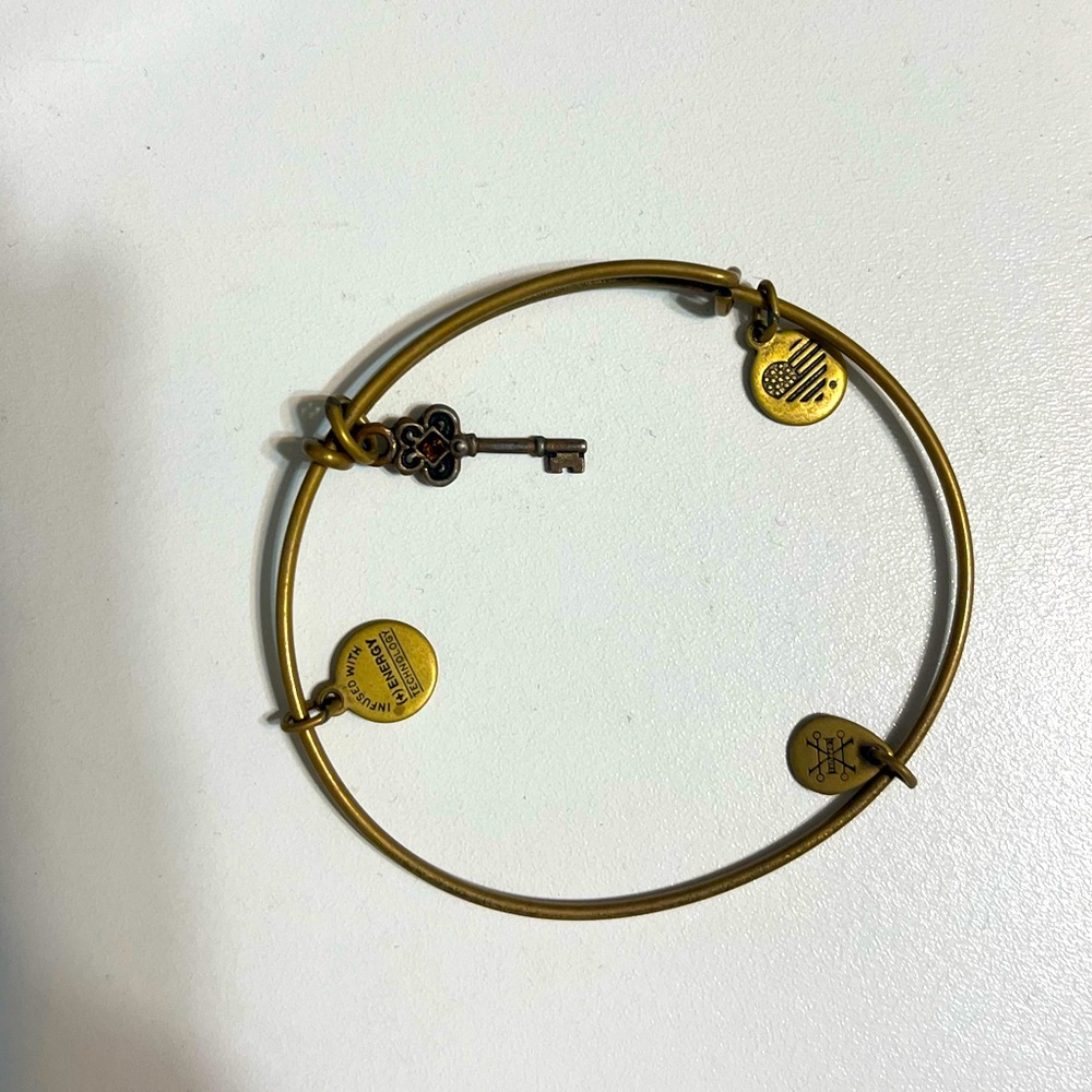 Alex and Ani gold colored key bracelet with topaz colored stone